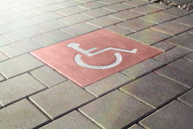 Röd symbolplatta med rullstolsmotiv i stadsmiljö
